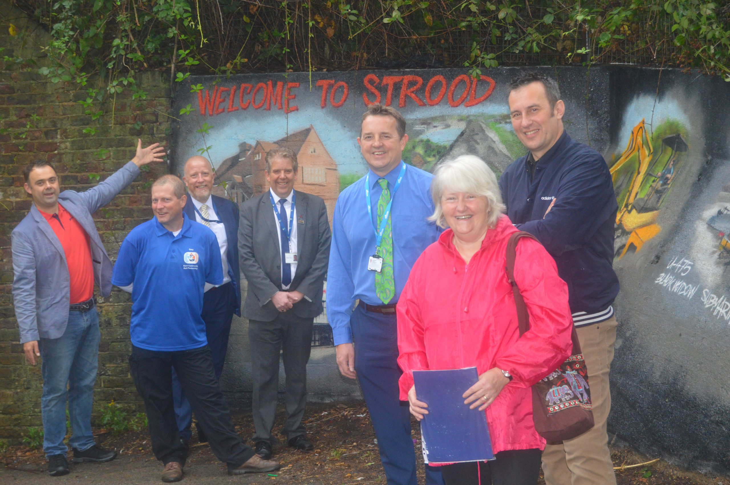 Members gathered in front of a community mural at Strood station.