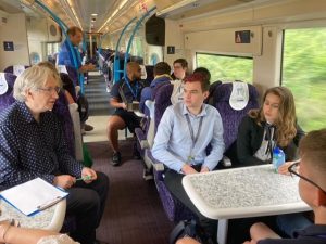 A group of students on a train being interviewed about their travel choices.