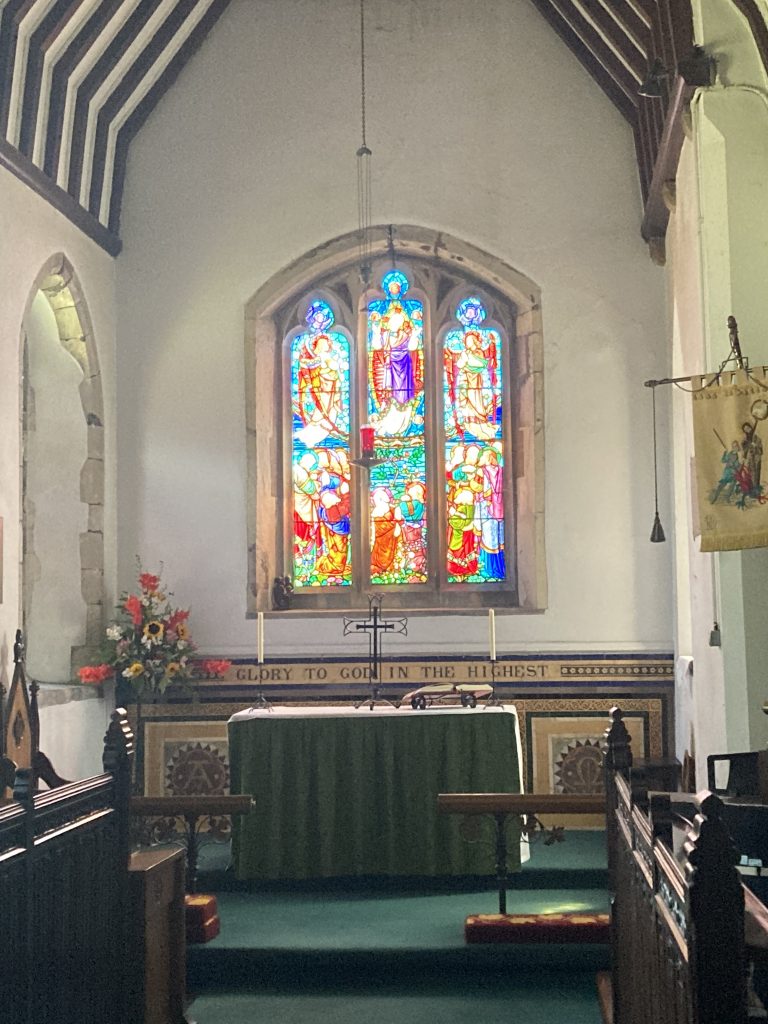 A bright stained glass window above an altar depicting religious scenes.