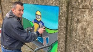 Artist at work on a mural depicting go-kart racing