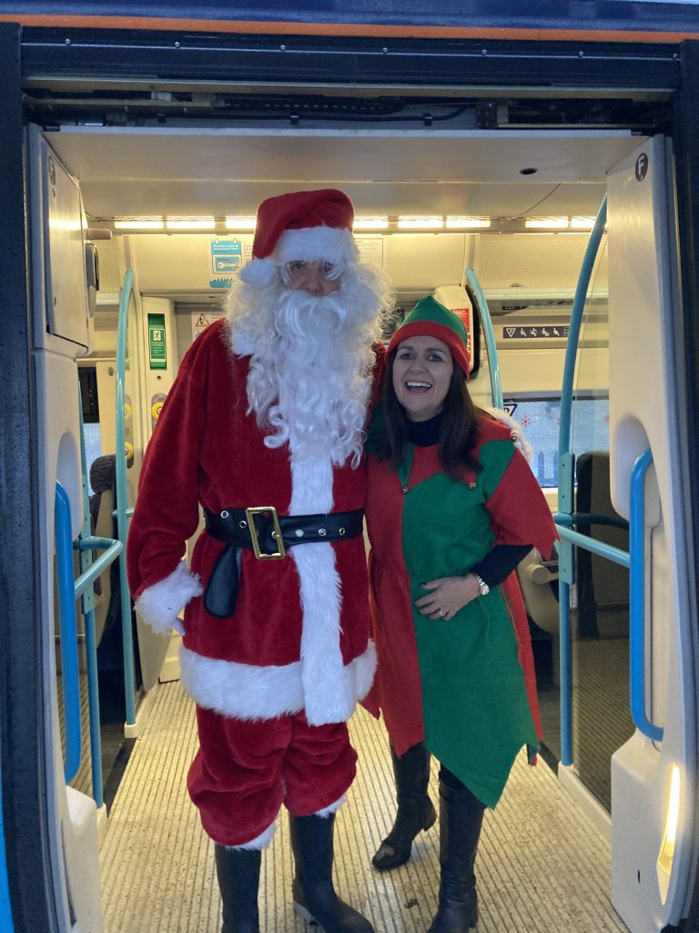 Santa and Elf Therese in the doorway of a train carriage.