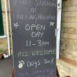 A chalk board outside the station "The station at Hollingbourne. Open Day 11-3PM All Welcome (Image of a Paw Print) Dogs Too!! Tea, coffee and squash (image of a steaming coffee cip on a saucer)