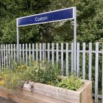 A large wooden planter full of colourful flowers on the station platform at Cuxton