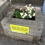 A planter on a platform with colourful flowers