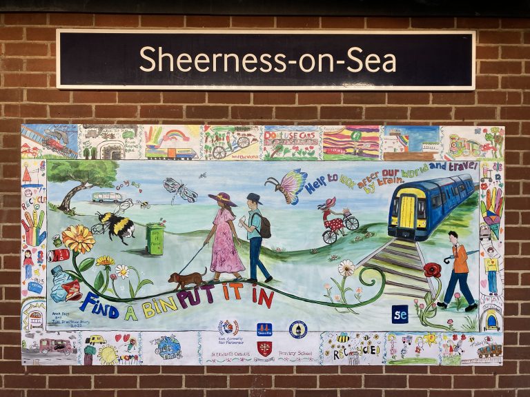 A colourful mural featuring peope walking, wheeling and cycling, and a train. There are a variety of sustainability themes.