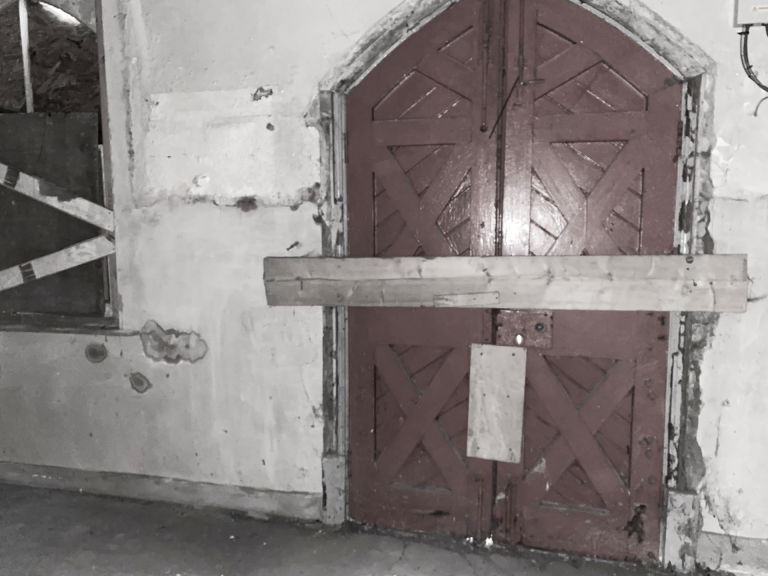 Inside a derelict station building. Boarded up and barred window and doors, peeling plaster on the walls