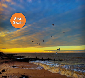 Visit Swale Logo - "Visit Swale" background picture of a beach at sunset.