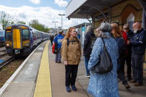 A group of people wait on a station platform as a train arrives.