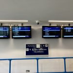 A row of four screens displaying train departure information