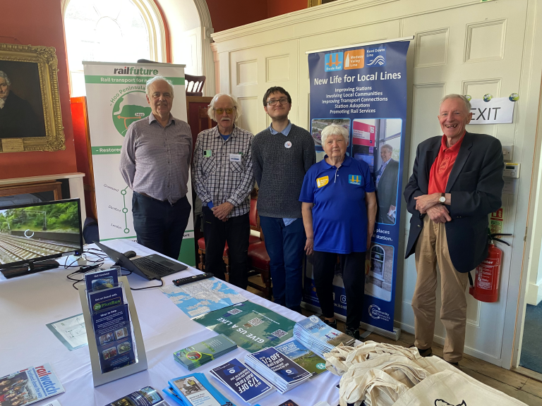 Gordon, Jackie, Dominic, Linda and Jonathan stood in front of banner displays for Rail Future and Kent Community Rail Partnership. In front of the group is a table packed with brochures and promotional materials