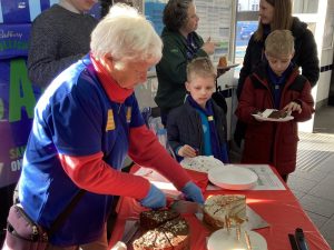 Linda cuts a cake for the Cub Scouts