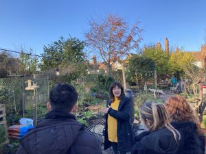 Suzanne delivers a tour of the garden to students, the view is of an allotment area