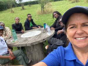 Selfie of Therese with a group of people sat at a large round wooden table.