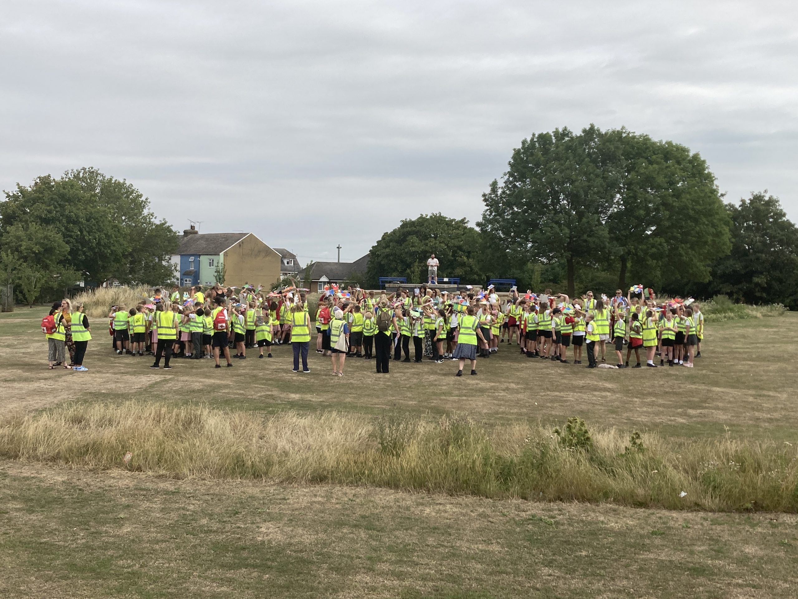 Young learners and their tutors assembled on the town green. They have formed three groups, outlining a "200" marked on the ground.