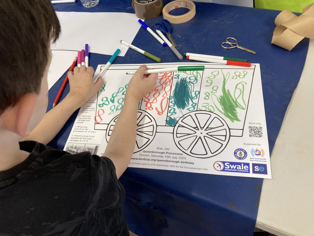 A child adds finishing touches to the decoration of their train carriage.