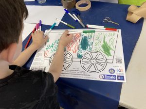 A child adds finishing touches to the decoration of their train carriage.