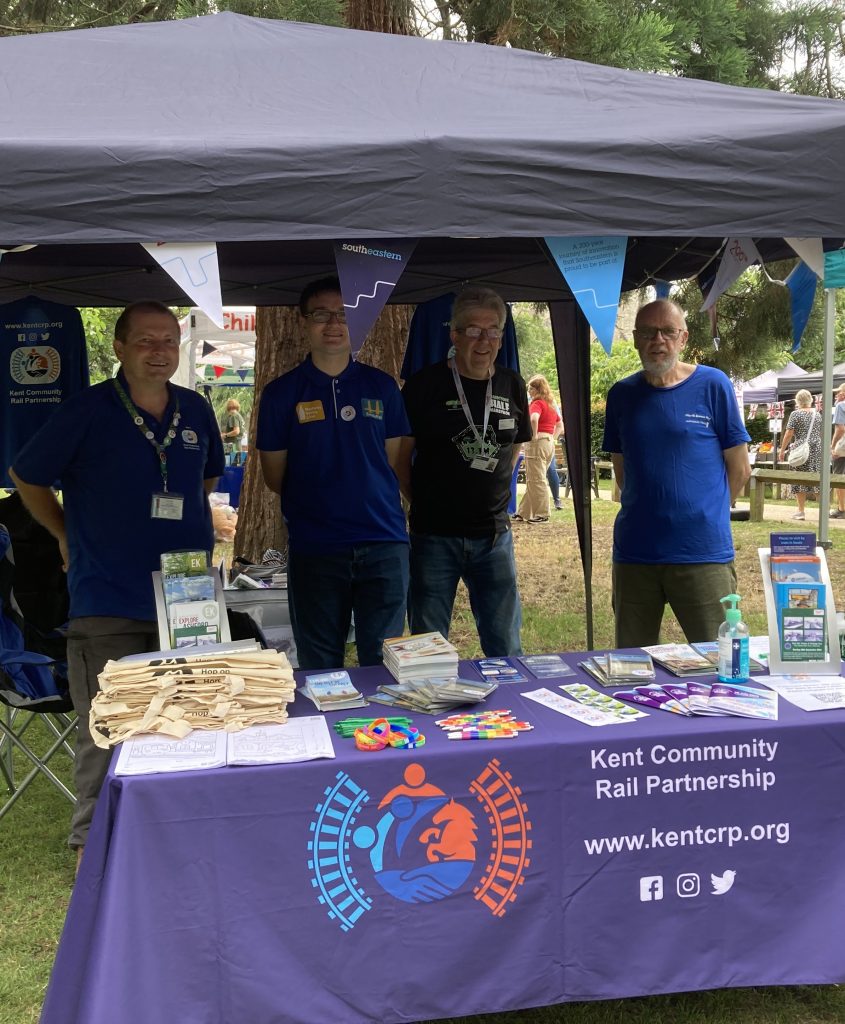 Matt, Gary, Dominic and Chris under a gazebo at our promotional stall. A table full of brochures and giveaways is set up in front of the team. Railway 200 Southeastern bunting lines the gazebo.