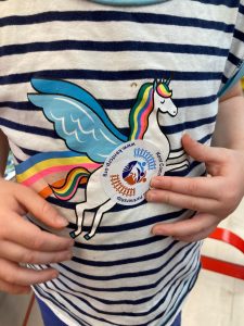 A child places a Kent Community Rail Partnership sticker onto their unicorn T-shirt