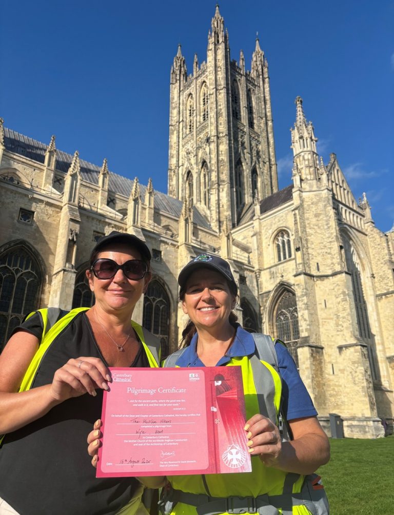 Sarah Moon and Therese Hammond pose with a Pilgrimage certificate. Canterbury Cathedral is in the background.