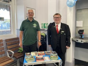 Jeff and Charley, Spa Valley Railway volunteers stood behing their table of promotional brochures in the station booking hall
