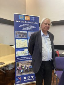 Clive English stood beside a roller banner promoting Kent Community Rail Partnership