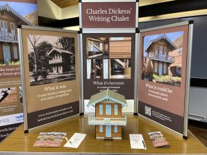 A model of a two storey chalet, based on that used by Charles Dickens. A surrounfding display seeks support for the restoration of the original building, Charles Dickens' Writing Chalet