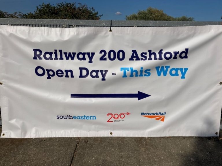 Banner on a railing. "Railway 200 Ahford open Day - This Way" An arrow pointing right. Logos of Southeasterm, Railway 200, and network rail.