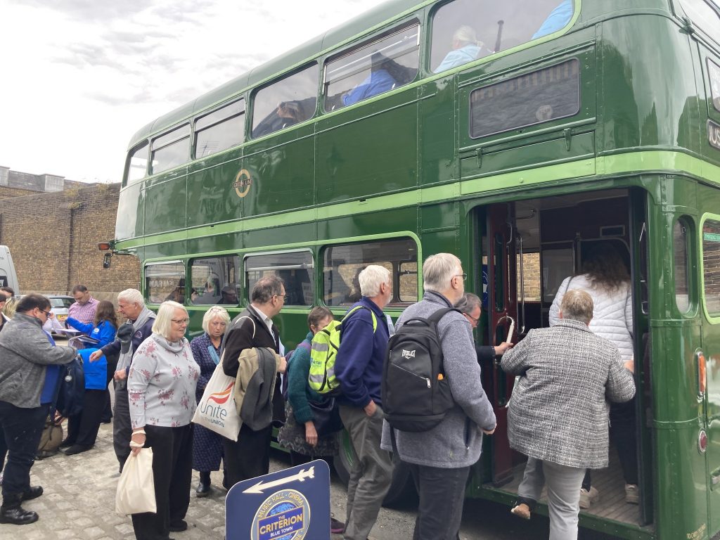A group of people board a green double decker bus