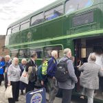 A group of people board a green double decker bus