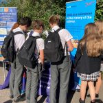 A group of students look at brochures from a display stand