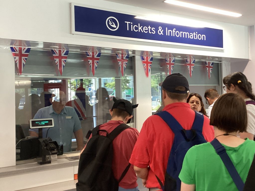 Students practice buying tickets from a staffed ticket office