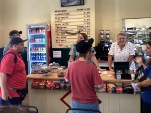 Students buy treats at a cafe counter, served by smiling staff