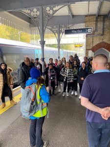 A group of people on a station platform prepare to board a train