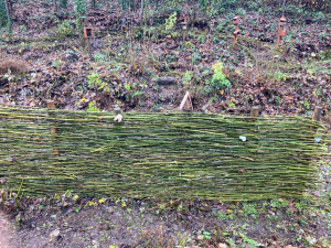 A weaved willow fence and bug hotels in the nature garden