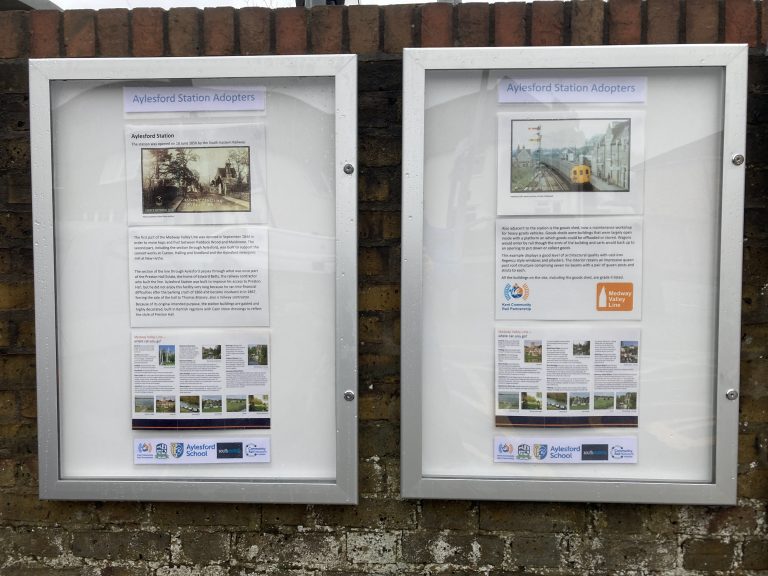 Two closed poster cabinets display information on Aylesford station's history.