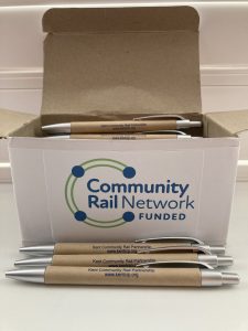 A box full of pens. The box is labelled Community Rail Network Funded. In front of the box are three pens with the wording Kent Community Rail Partnership, kentcrp.org