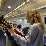 An image of Claire, the musician, singing with her guitar.