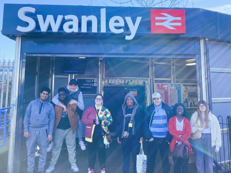 A group of people pose for a photo at the entrance to Swanley station.
