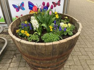 A wooden planter of colourful flowers on a station platform