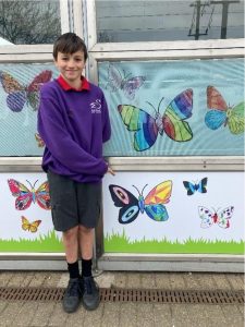 A young person points at images of butterflies, vinyl displays on a wall