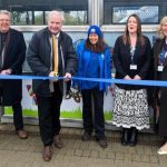 A person cuts a ribbon while others look on