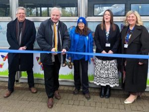 A person cuts a ribbon while others look on