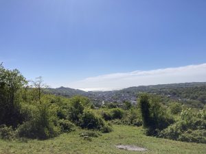 A view from the lush green hillside of Oldpark Hill across Dover with the harbour and the sea in the distance.