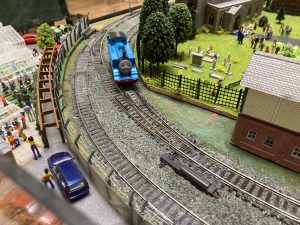 A model railway layout with Thomas the Tank engine, a small blue stean locomotive on the tracks