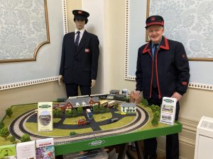 Mark Jones, the Herne Bay Railway historian, with a model railway layout. Mark is wearing a vintage British Rail uniform. A dummy in vintage railway costume is in the background.