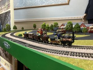 A model of an early steam engine with passengers in open carriages on a track layout