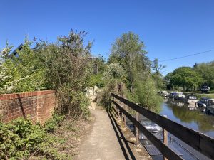 A narrow path beside a river, with a railing to prevent falls.