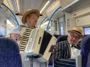 Two musicians performng aboard a train.