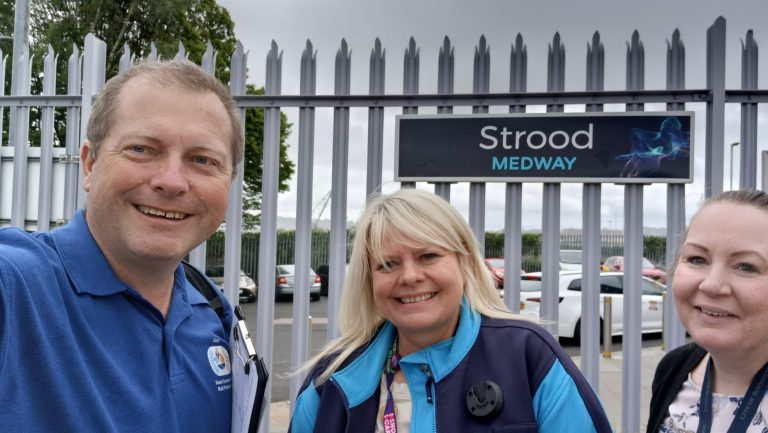 Selfie of Gary, Bev and Charlotte in front of a sign for Strood station.