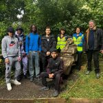Students and walk leaders pose for a picture alongside the carved wooden statue of Percy the Pilgrim.